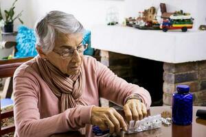 anziano donna a casa organizzazione sua prescrizione farmaci in un' settimanalmente pillola organizzatore foto