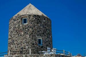 antico mulino a vento pietra Torre su il bellissimo villaggio di imerovigli a santorini isola foto