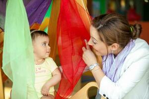 bellissimo dieci mesi bambino ragazza giocando con colorato tessuti e sua mamma. presto stimolazione per bambini piccoli concetto. foto