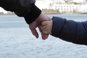 padre e figlio si tengono per mano foto