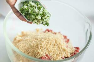 passo di passo levantino cucina kibbeh preparazione. aggiungendo il ingredienti per preparare kibbeh in un' ciotola foto