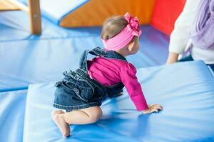 bellissimo dieci mesi bambino ragazza strisciando su un' colorato sfondo. presto stimolazione per bambini piccoli concetto. foto