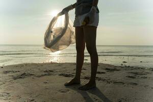 volontario raccogliere su spazzatura spazzatura a il spiaggia e plastica bottiglie siamo difficile decomporsi impedire danno acquatico vita. terra, ambiente, greening pianeta, ridurre globale riscaldamento, Salva mondo foto