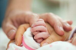 avvicinamento di un' neonato e sua genitori mani a ospedale su il giorno di sua nascita. famiglia concetto. paternità concetto foto