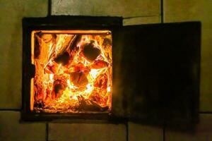 bellissimo camino antico con fuoco a fiamma leggera per il riscaldamento della stanza dell'edificio foto