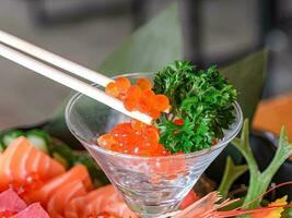 salmone uova, salmone caviale o ikura nel un' cocktail bicchiere guarnito con le foglie. utilizzando bastoncini foto