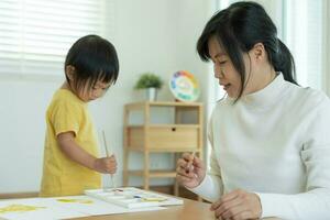 contento Asia madre giocando apprendimento dipingere per poco ragazza. divertente famiglia è contento e eccitato nel il Casa. madre e figlia avendo divertimento la spesa tempo insieme. vacanza, attività foto