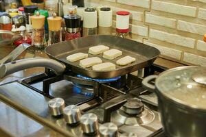 halloumi formaggio è fritte su costine padella al di sopra di fuoco su gas stufa foto