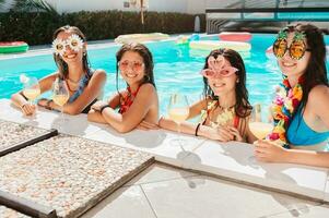 gruppo di amici nel costume da bagno bevanda un' cocktail nel un' nuoto piscina foto