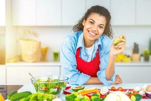giovane donna nel il casa cucina prepara un' genuino insalata con fresco verdure foto