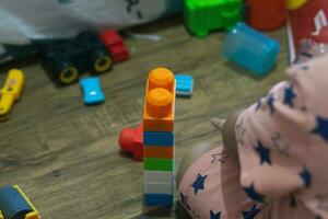 poco ragazzo giocando con giocattoli seduta su il pavimento tra sparpagliato giocattoli, un' pasticcio nel il figli di camera foto