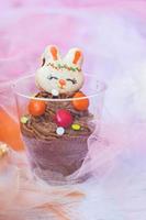 mousse al cioccolato in bicchiere di plastica trasparente, decorata con biscotto a forma di coniglio