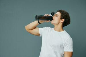 isolato uomo tipo atletico in forma maglietta bottiglia esercizio bevanda acqua sport foto