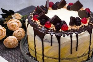 bella torta festiva con glassa al cioccolato e marmellata su uno sfondo di fiori