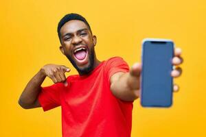 mano uomo giallo tecnologia contento mobile Telefono giovane africano studio nero sfondo foto