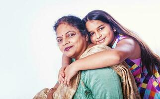 carino poco indiano ragazza in posa con sua nonna al di sopra di bianca sfondo foto