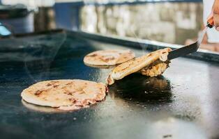 spatola assunzione un' tradizionale formaggio pupusas su il griglia, vicino su di tradizionale artigiano grigliato pupusas. tradizionale nicaraguense pupusas con fuso grigliato formaggio foto