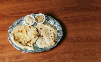 tradizionale pupusas servito con insalata su il tavolo. superiore Visualizza di Due nicaraguense pupusas servito con insalata su il tavolo. delizioso salvadoregno pupusas con fuso formaggio su di legno tavolo foto