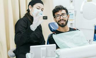 dentista con paziente mostrando lui un' periapicale raggi X, Visualizza di dentista con paziente rivedere dentale raggi X. dentista mostrando periapicale raggi X per paziente foto