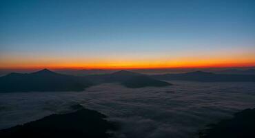 bellissimo paesaggio su il montagne contro cielo durante Alba. spettacolare Visualizza nel nebbioso valle coperto foresta sotto mattina cielo. campagna paesaggio Visualizza sfondo. foto