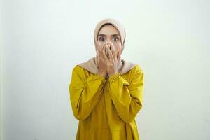 scioccato giovane asiatico musulmano donna vestito nel bianca copertura bocca con mano per sbaglio isolato su bianca sfondo foto