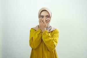 scioccato giovane asiatico musulmano donna vestito nel bianca copertura bocca con mano per sbaglio isolato su bianca sfondo foto