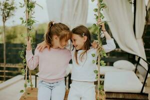 carino poco ragazze su il swing nel il Casa Giardino dietro la casa foto