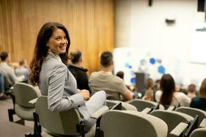 giovane donna seduta nel pubblico su conferenza o laboratorio foto