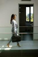 giovane attività commerciale donna a piedi con ventiquattrore nel il ufficio corridoio foto