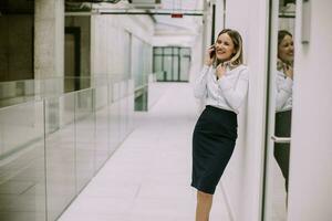 giovane attività commerciale donna utilizzando mobile Telefono nel il ufficio corridoio foto