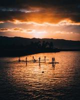 silhouette di stand up paddleboarder durante il tramonto nella costa nord, oahu, hawaii foto