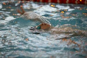 ragazzo nel un' nuoto berretto e nuoto occhiali nel il piscina. il bambino è impegnato nel il nuoto sezione. foto