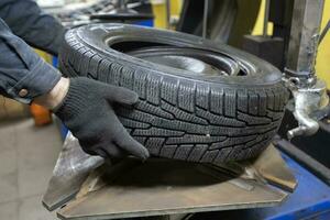 pneumatico servizio. il meccanica mani hold il ruota di il macchina. ruota riparazione. foto