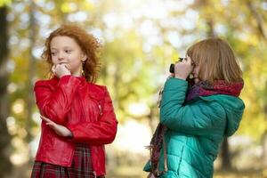 Due dai capelli rossi ragazze amiche fotografia ogni altro nel il autunno parco con un' retrò telecamera. foto