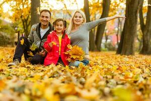 un' famiglia godendo d'oro le foglie nel autunno parco foto