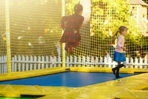 contento scuola ragazza salto su trampolino nel il autunno parco foto