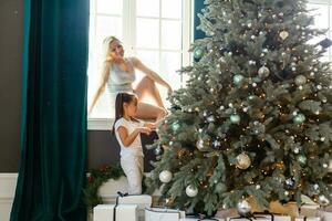 contento famiglia madre e bambino ragazza vicino un' Natale albero con Natale presente foto