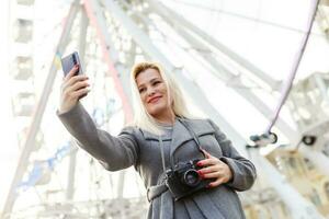 il giovane ragazza passeggiate in giro il città vicino luoghi d'interesse. Ferris ruota. divertimento parco. autunno foto