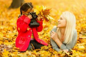 contento famiglia madre con sua figlia giocando e ridendo su autunno camminare foto