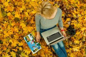 donna con il computer portatile e foto libro nel autunno parco