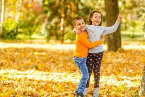 bambini che giocano con le foglie cadute autunnali nel parco foto