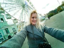 il giovane ragazza passeggiate in giro il città vicino luoghi d'interesse. Ferris ruota. divertimento parco. autunno foto