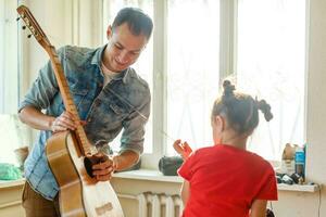 avvicinamento dell'uomo mano mutevole stringhe su il suo vecchio acustico chitarra. foto