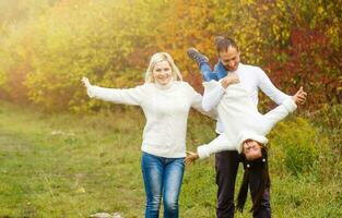 concetto della famiglia, dell'infanzia, di stagione e della gente - famiglia felice nel parco di autunno foto