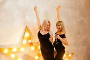 Natale. banchetto. Due contento festivo giovane moda donne con vino bicchieri di Champagne tostatura - nuovo anno foto