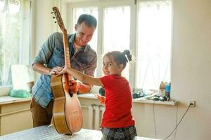 avvicinamento dell'uomo mano mutevole stringhe su il suo vecchio acustico chitarra. foto