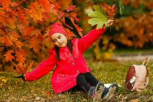 allievo di primario scuola con libro nel mano. ragazza con zaino vicino edificio all'aperto. inizio di Lezioni. primo giorno di autunno. foto