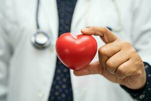 medico che tiene un cuore rosso nel reparto ospedaliero, concetto medico sano e forte. foto