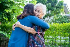 asiatico anziano donna abbraccio con sua figlia con amore, cura, aiuto, incoraggiare e empatia a parco, salutare forte medico concetto. foto