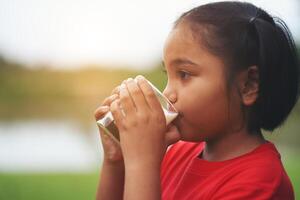 bambina che beve latte nel parco foto